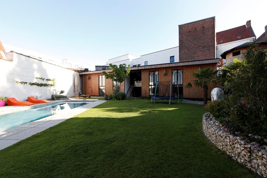 Loungezetels en groene beplanting rond het verwarmde zwembad in de tuin van Koto